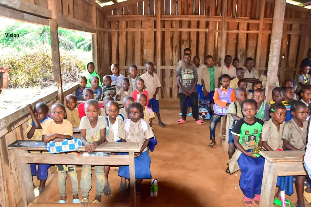 Élèves assis dans une salle de classe en planches, au village
