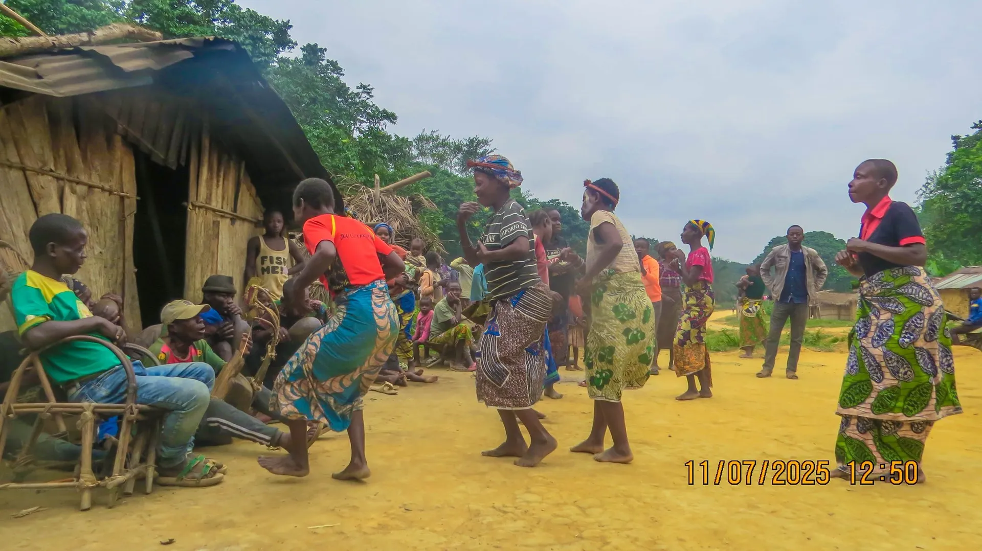 Habitants d’un campement autochtone dansant devant les cases